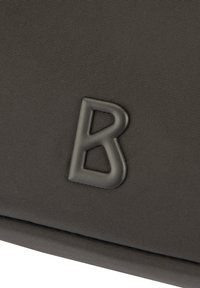 Grå tygväska med en texturerad yta och en framträdande, upphöjd svart bokstav "B" som en utmärkande detalj.