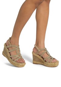 Beige wedge sandalen met een gelijkmatig textuurstof bovenwerk, voorzien van kruislings gestructureerde bandjes en sprankelende accenten, op een geweven jute plateauzool.