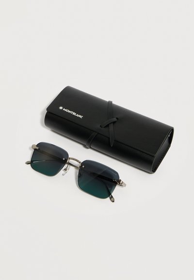 Μαύρα γυαλιά ηλίου με τετράγωνους φακούς και ασημένιο μεταλλικό πλαίσιο, τοποθετημένα δίπλα σε μαύρη δερμάτινη θήκη Montblanc με κλείσιμο τύπου περιτύλιξης.