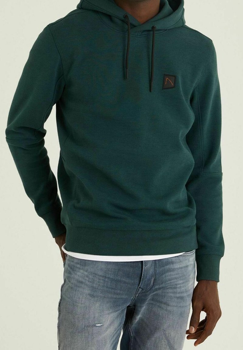 Felpa con cappuccio verde in tessuto texturizzato, con coulisse regolabili e un patch logo sul petto. Vestibilità casual con polsini a coste.