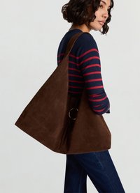 Brown suede tote bag with a structured triangle shape, featuring a gold ring accent and a wide shoulder strap.