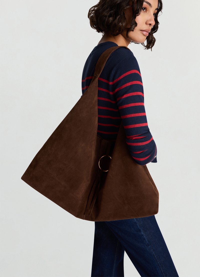 Brown suede tote bag with a structured triangle shape, featuring a gold ring accent and a wide shoulder strap.