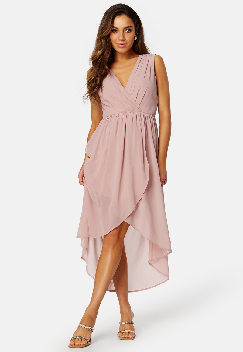Różowa sukienka z szyfonu w odcieniu blush, z głębokim dekoltem w kształcie litery V, bez rękawów i asymetrycznym dołem. Posiada zdobienie w talii i miękką, zwiewną fakturę.