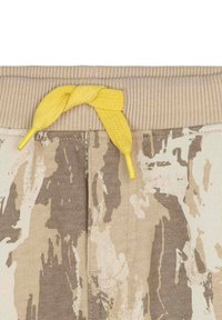 Pantaloni della tuta con motivo mimetico, in una combinazione di colori beige e marrone, caratterizzati da una vita a coste e da un laccio giallo intrecciato.