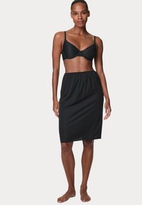 Reggiseno nero con spalline regolabili abbinato a una gonna slip nera, lunga fino al ginocchio, con vita elastica. Tessuto morbido con un design aderente.