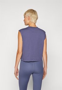 Sleeveless, cropped top in soft purple fabric. Features a round neckline and stitched hem. Paired with matching fitted leggings.