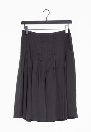 Černá plisovaná sukně z hladké látky, s přiléhavým pasem a splývavým střihem s několika vertikálními plisé. Visí na jednoduchém černém ramínku.