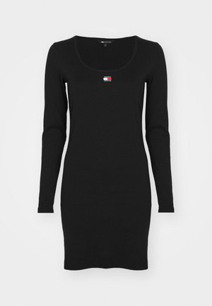Rochie neagră cu mâneci lungi, decolteu rotund, ajustată pe corp, confecționată dintr-un material moale. Prezintă un mic logo multicolor centrat pe piept.