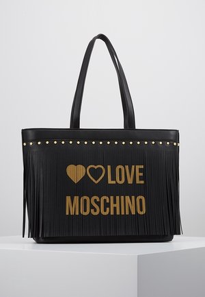 Czarna skórzana torba typu tote z frędzlami, złotymi ćwiekami wzdłuż górnej krawędzi oraz złotym napisem "Love Moschino" z dwoma symbolami serca z przodu.