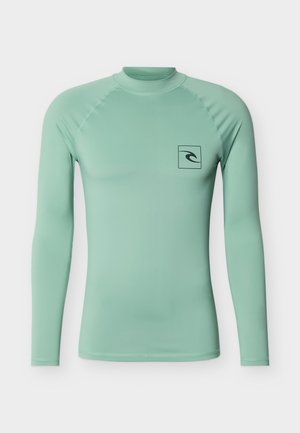 Camiseta de manga larga para surf en verde claro, con un pequeño logo de onda negra dentro de un cuadrado en el pecho izquierdo, con cuello alto redondo.