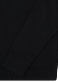 Detail černého pleteného svetru s hladkou texturou, žebrovanými manžetami a lemem. Tkanina má jednotný vzhled bez vzorů.