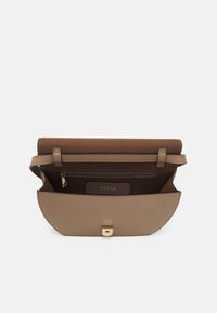 Bolso de mano de cuero marrón con una textura suave, forma curvada, herrajes dorados y un bolsillo interior con cremallera. Presenta un logotipo en el interior.