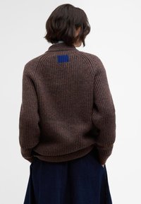 Brown ribbed knit sweater with a high collar and blue square detail on the back. Features wide cuffs and a relaxed fit.