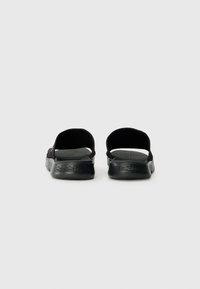 Zwarte sandalen met open achterkant, textielen bovenkant en gevoerd voetbed. Minimalistisch ontwerp met een gladde, textuurgegeven zool en details van elastische banden.