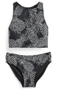 Svart baddräkt i två delar som består av en ärmlös croptop och underdel, prydd med vita ananasteckningar och en slät, elastisk textur.