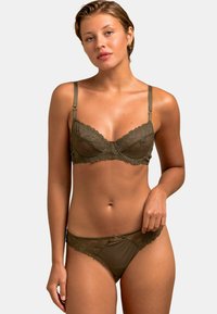 Soutien-gorge en dentelle vert olive et culotte assortie avec des sections en mesh transparent, des bords festonnés et de délicats motifs floraux. Bretelles réglables incluses.