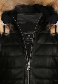 Giacca in pelle nera con design trapuntato, dotata di cappuccio foderato in pelliccia, zip argentata e etichetta interna con marchio.