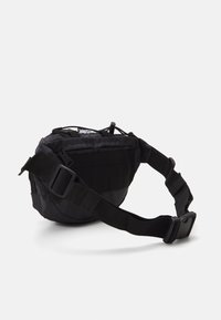 Marsupio nero in nylon con tracolla regolabile, forma arrotondata, tasca frontale con zip e fascia in tessuto per attacchi modulari. Finitura opaca, design leggero.