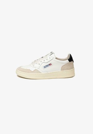 Sneaker bianco in pelle con accenti in suede beige e neri. Presenta una punta perforata, lacci flat e suola in gomma con scanalature.