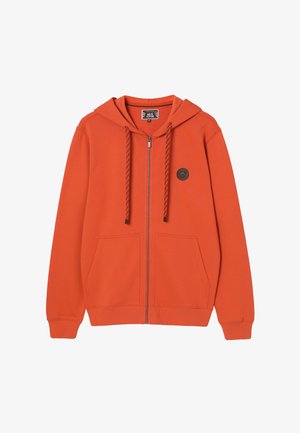 Oranssi vetoketjullinen huppari, jossa on kiristysnyörit, etutaskut, resorireunukset ja pieni pyöreä karhuembleemi vasemmassa rintapäässä.