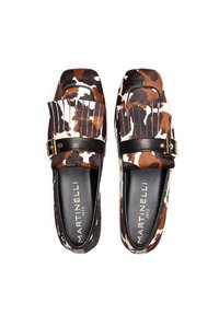 Mocasines de piel de vaca con un diseño marrón y blanco a rayas, que presentan detalles en cuero negro, flecos y una hebilla metálica.