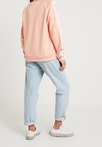 Vaaleanpunainen urheilupaita valkoisilla raitoja, rento istuvuus, resorikaulukset, yhdistetty vaaleansinisiin farkkuihin ja valkoisiin tennareihin.