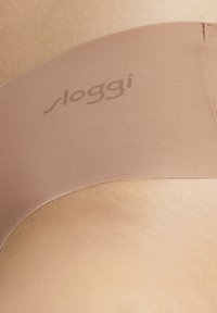 Beige stretchboxers met ribbeltextuur en een gladde afwerking. Subtiel gedrukt "sloggi" logo op de tailleband.