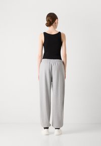 Zwarte geribbelde tanktop met een ronde hals, gecombineerd met losse, lichtgrijze joggingsbroek met een elastische tailleband en taps toelopende boorden.