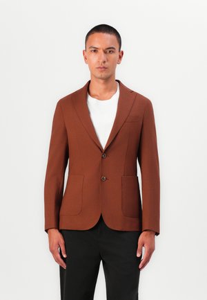 Brown blazer featuring a notch lapel, two front pockets, and two buttons. Worn over a white shirt, with a smooth texture.