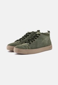 Adidași înalți din suede verde, cu talpă din cauciuc, vârfuri rotunde și șireturi contrastante. Prezintă detalii de cusătură și o bucată de prindere în spate.