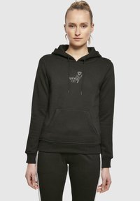 Haut à capuche noir en tissu doux, doté d'une poche avant, d'un cordon de serrage pour la capuche et d'un imprimé graphique avec "spring VIBES" sur la poitrine.