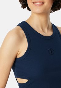 Marineblauw aansluitend tanktop met ribbeltextuur, met uitsneden aan de zijkanten en een klein geborduurd logo op de borst.