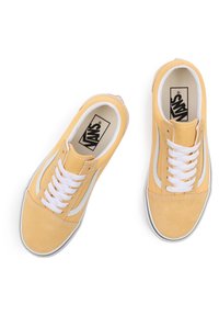 Sneakers marki Vans w żółtym zamszu z białymi sznurówkami, z białym zakrzywionym pasek po boku i kontrastującym czarnym logo na języku. Płaska gumowa podeszwa.