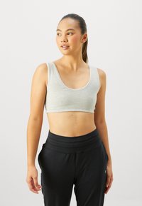 Gray cotton crop top with a scoop neckline and contrasting trim, paired with black high-waisted pants, featuring a smooth texture and fitted design.