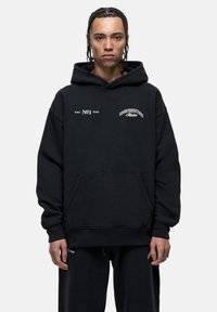 Felpa nera con cappuccio e tasca anteriore, caratterizzata da accenti di testo bianchi e un grande logo. Realizzata in morbido tessuto, ha una vestibilità comoda e un cappuccio.