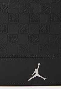 Fekete bőr pénztárca, dombornyomott "23" mintával, texturált felülettel és ezüst Jumpman logóval.