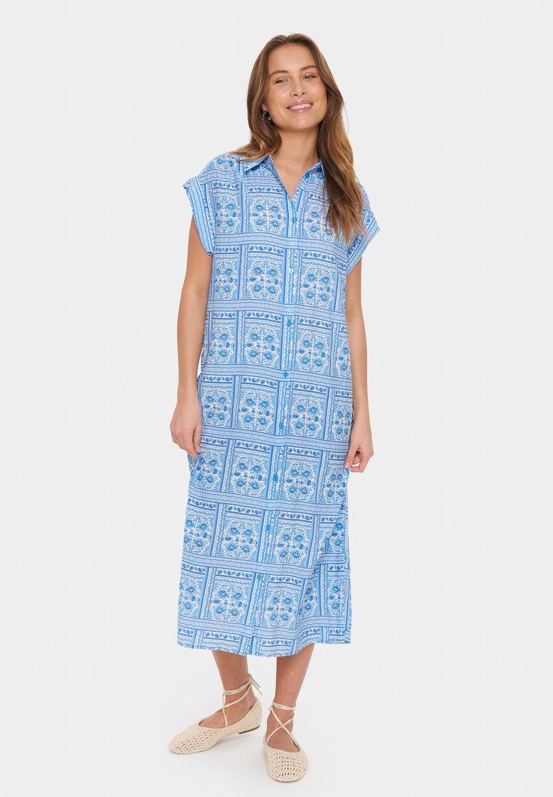 Blå mönstrad knäppning midi-klänning med kort ärm, med blommotiv och avslappnad passform, parat med ljusbeiga snörskor.