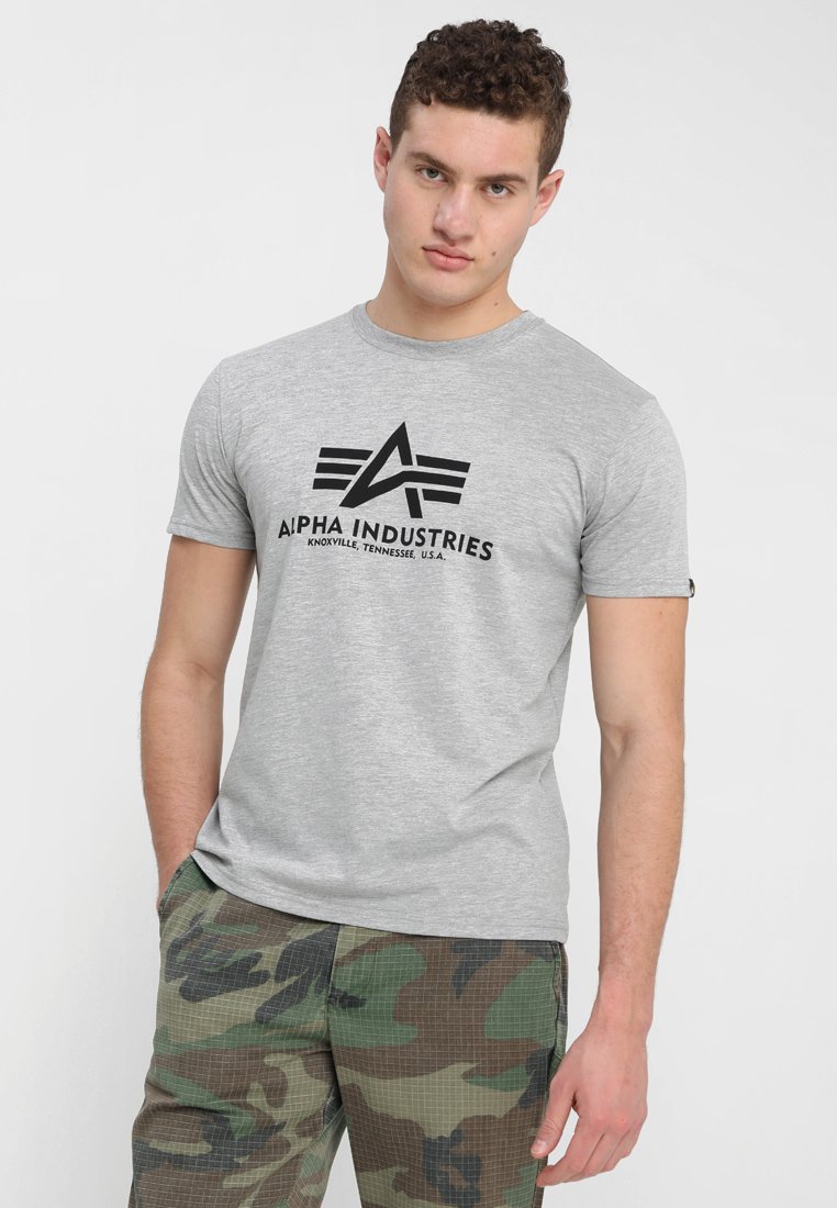 Grå bomulds t-shirt med et sort grafisk logo med vinklet design, parret med camouflage cargo bukser. Korte ærmer og rund halsudskæring.