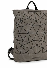 Mochila gris con líneas geométricas negras, una asa negra y "SURI FREY" impreso en la parte inferior delantera.