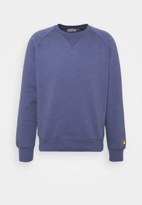 Sudadera morada hecha de una tela suave, con cuello redondo, puños acanalados y un pequeño logo en la manga izquierda.