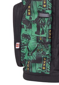 Sac à dos noir avec un design graphique vert mettant en scène des personnages ninja. Le tissu est lisse et il possède une étiquette de logo LEGO sur le côté.