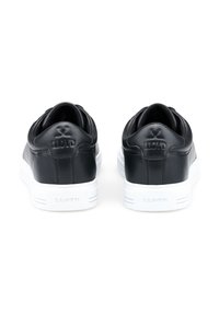 Schwarze Leder-Sneaker mit glatter Oberfläche, ausgestattet mit weißen Gummisohlen und geprägtem Branding an der Ferse. Minimalistisches Design ohne Muster.