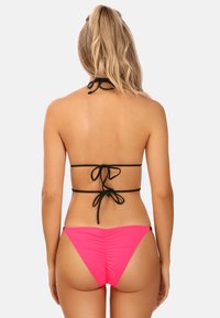 Czarny biustonosz bikini ze sznurkiem, z dekoltem halter i związywaniem z tyłu, w zestawieniu z jasnoróżowymi, niskopodwieszonymi majtkami z marszczeniem. Gładka tekstura materiału.