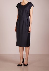 Tmavě modré šaty ke kolenům s kulatým výstřihem a krátkými rukávy. Vyrobené z hladkého materiálu s přiléhavým střihem a bočními kapsami.