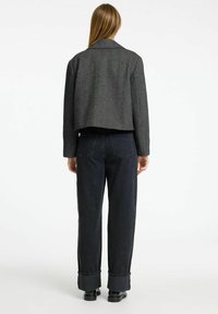 Giacca accorciata a spina di pesce grigia con collo classico, abbinata a jeans a vita alta blu scuro con risvolti. Tessuto testurizzato.