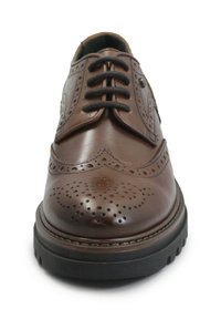 Scarpa brogue in pelle marrone con perforazioni decorative, punta tonda, suola in gomma nera e chiusura con lacci. Presenta dettagli di cuciture accentuate.