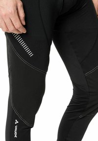 Sorte trenings leggings laget av elastisk stoff, med hvite reflekterende detaljer og et ergonomisk design med teksturert overflate.