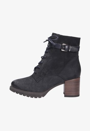 Bottines noires en daim, avec un laçage à l'avant, une sangle latérale avec boucle et un talon en bois épais. Semelle à motif texturé.