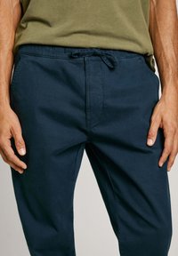 Verenna siniset rentopö trousers, joissa on naru vyötärö, kevyttä kangasta, sivutaskuja ja sileä tekstuuri. Rentoa muotoilua jokapäiväiseen käyttöön.