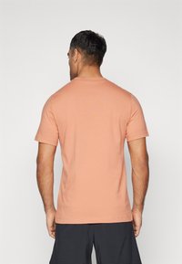 T-shirt met korte mouwen van zacht koraalkatoen, ronde hals, gladde textuur en een eenvoudig ontwerp; geen zichtbare logo's of patronen.